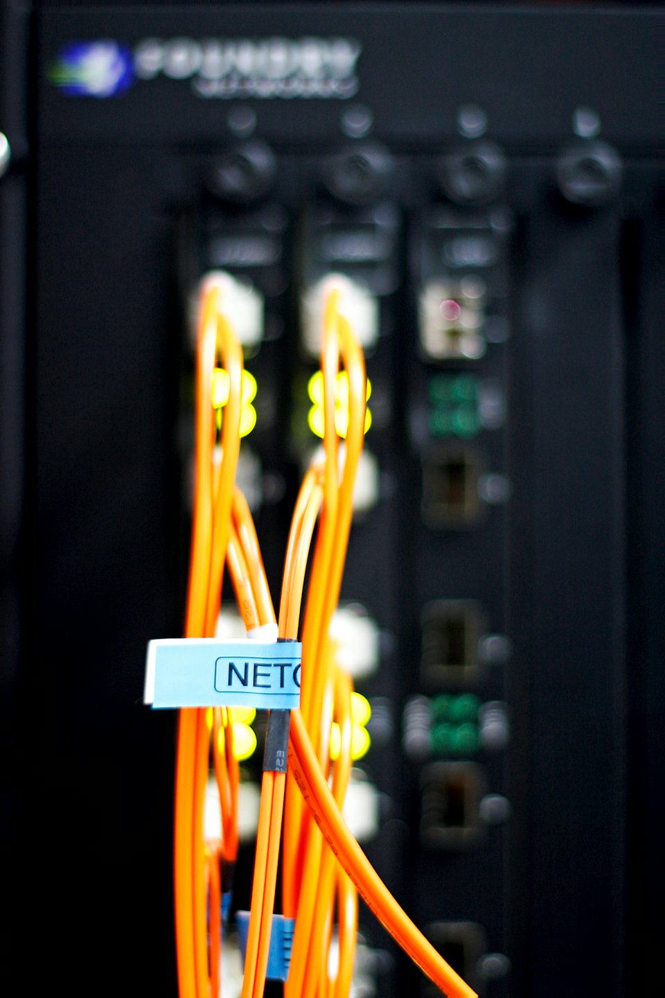 Bundle of orange fiber optic cables connected to a network switch.